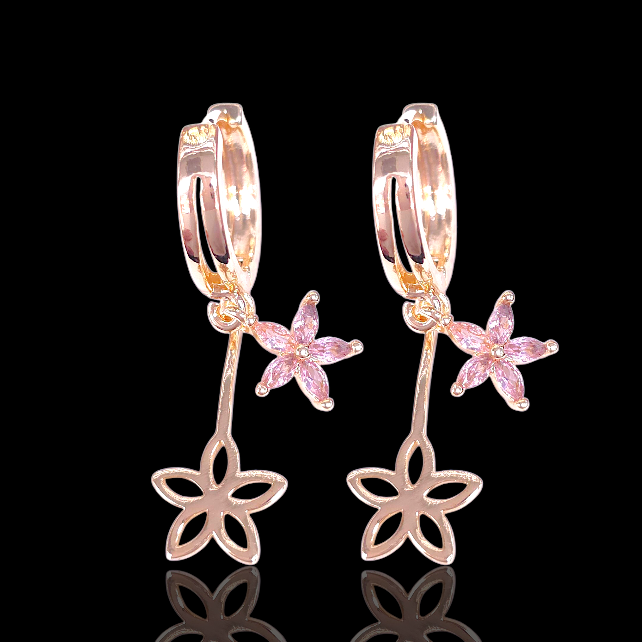 Rose gold floral earrings with pink gemstones on a black background